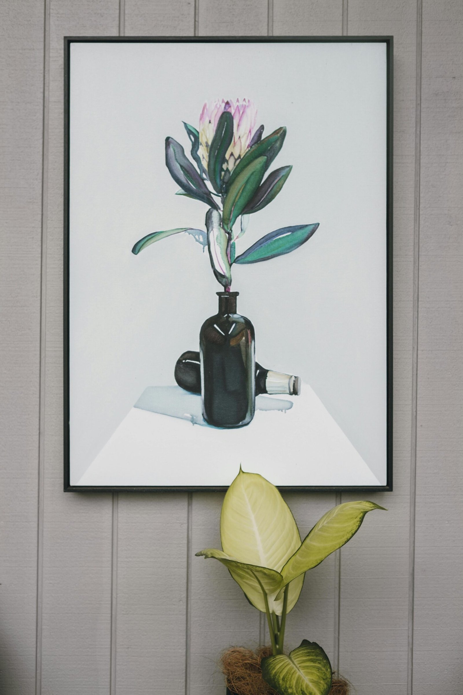 Stylish wall art featuring a botanical painting above a live houseplant.